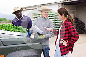 Girl manager discussing with workers delivery of seedlings to farm