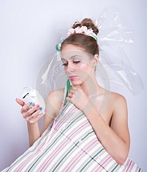 Girl-marshmallow with a pillow and alarm clock in her hands.