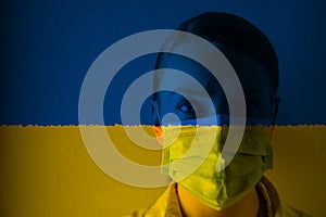 Girl in a mask against the background of the Ukraine flag, coronavirus, danger and threat, outbreak of a dangerous virus. Photo