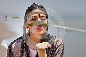 Girl in mask bandari woman sends air kiss, Southern Iran.