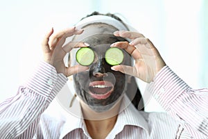 Girl with mask on her face shows slices cucumbers