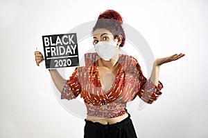 Girl with mask raising her hands and shoulders in show of resignation and conformity and holding a Black Friday 2020 poster with