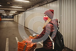 Girl with mask and shooping cart in the garage