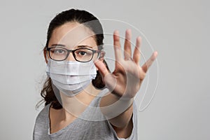 A girl in a mask shows a stop gesture fearing for the health of people