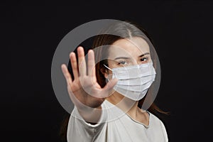 A girl in a mask shows a stop gesture fearing for the health of people