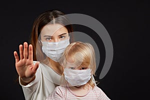 A girl in a mask shows a stop gesture fearing for the health of people