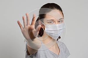 A girl in a mask shows a stop gesture fearing for the health of people