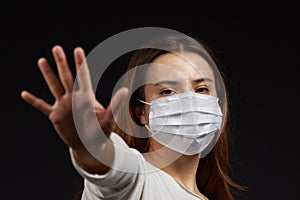 A girl in a mask shows a stop gesture fearing for the health of people