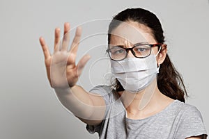 A girl in a mask shows a stop gesture fearing for the health of people