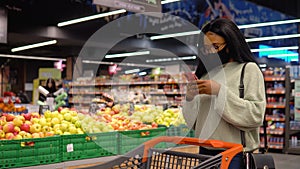 Girl in a mask talking on the phone in the supermarket. Shopping concept