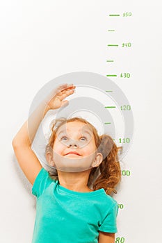 Girl measure height with hand looking up