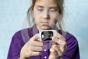 girl measures her blood oxygen saturation on a blue background.