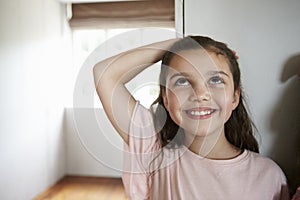 Girl Measuring Height Standing Against Wall At Home