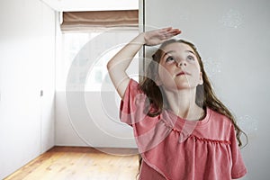 Girl Measuring Height Standing Against Wall At Home photo