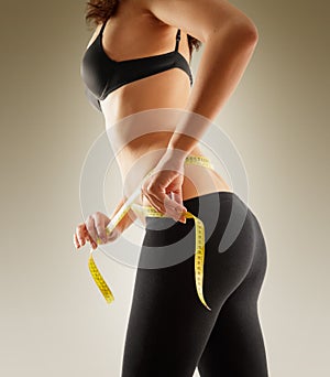 Girl measuring her waist with tape measure