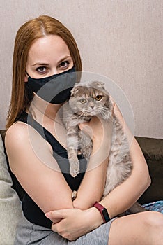 Girl in a medical mask with a cat in her arms