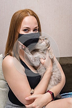 Girl in a medical mask with a cat in her arms