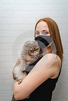 Girl in a medical mask with a cat in her arms