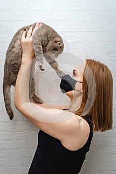 Girl in a medical mask with a cat in her arms