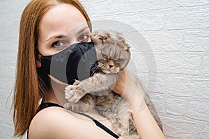 Girl in a medical mask with a cat in her arms