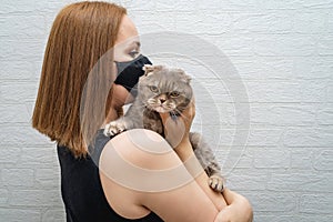 Girl in a medical mask with a cat in her arms