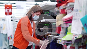 Girl in medical mask choosing skirt in clothes department during COVID