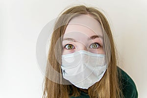Girl in a medical mask closeup surprised, bulging, scared eyes