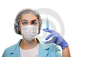 A girl in a medical mask, gloves and a robe with a syringe in his hands on a white background. Beautician, beauty specialist.