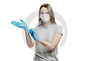 A girl in a medical mask puts on latex blue gloves on her hands. Precautions during coronavirus rendezvous. Isolated on a white