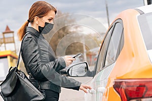 Girl in medical mask rents car for a trip to the hospital. The concept of noncash payment on the mobile app