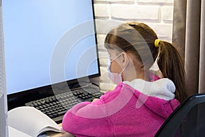 A girl in a medical mask sits at a computer and does homework, free space on the screen