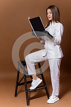 Girl medical worker in black gloves in a white suit with a magazine in her hands