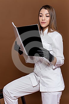 Girl medical worker in black gloves in a white suit with a magazine in her hands