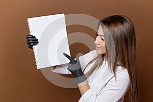 girl medical worker in black gloves in a white suit with a magazine in her hands