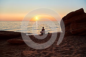 Girl meditate in calm sunset evening sit on sand. Idea of summer time and time to relax. Desire of adventure concept