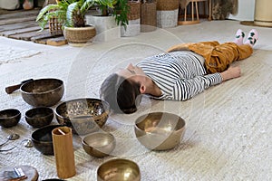 Girl meditate with singing bowls during tibet massage and sound therapy. Tibetan spiritual practices