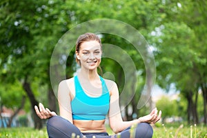 Girl meditates in lotus pose on green grass