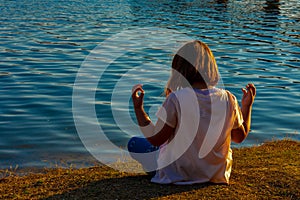 Girl meditating by the lake during the golden hour