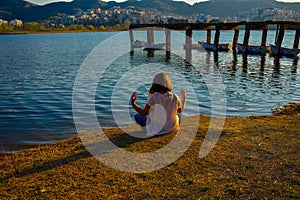 Girl meditating by the lake during the golden hour