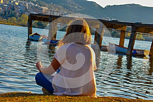 Girl meditating by the lake during the golden hour