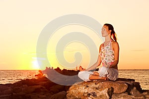 Girl meditating on rocks.