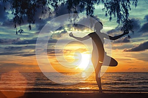 Girl meditating on the sea beach during a wonderful sunset. Yoga and fitness.