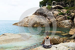 The girl meditating on stones by the sea, the Girl borrowing with yoga the island Samui, yoga in Thailand. photo