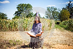 Girl meditating on a tump in a meadow