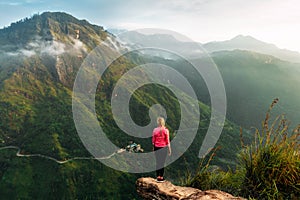 Girl meets sunrise in the mountains. Girl traveling to Sri Lanka. Mountain sports. Athlete happy finish. Mountain tourism. Walking