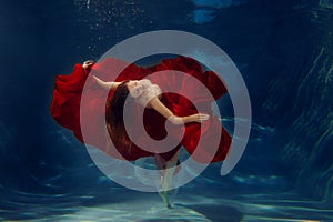 Girl mermaid. Underwater scene. A woman, a fashion model in the water in a beautiful dress swims like a fish