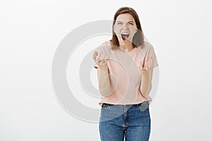 Girl in middle of argue, yells and screams, being angry and off, bending towards camera, gesturing with hands
