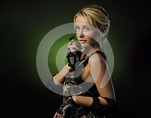 a girl in military airsoft clothes with a grenade in her hands on a dark background