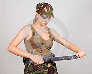 The girl in the military, buttons bandolier. Gray background.