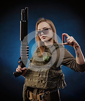 The girl in military overalls airsoft posing with a gun in his hands on a dark background